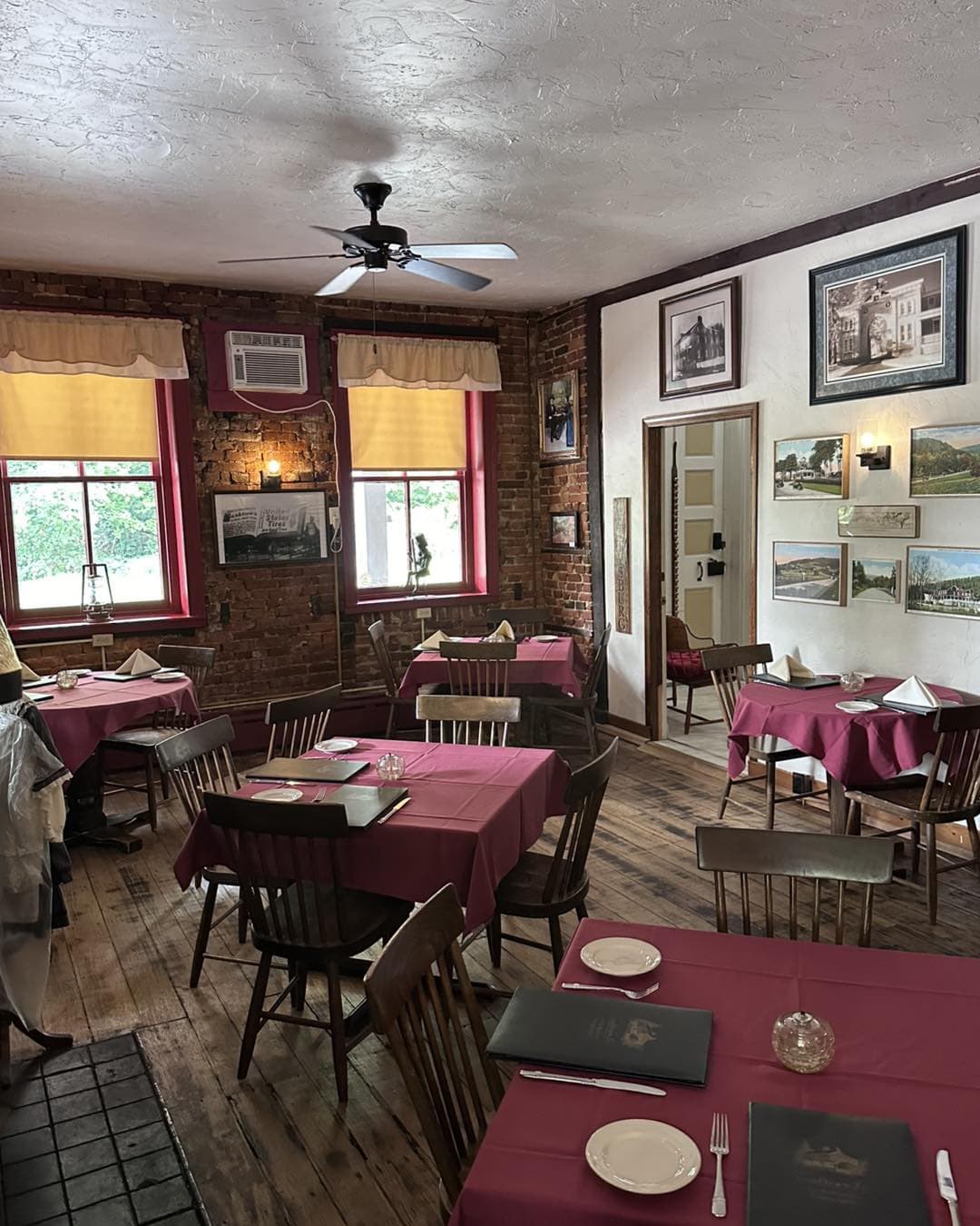 A cozy restaurant interior with red-checked tables, brick walls, and framed artwork.