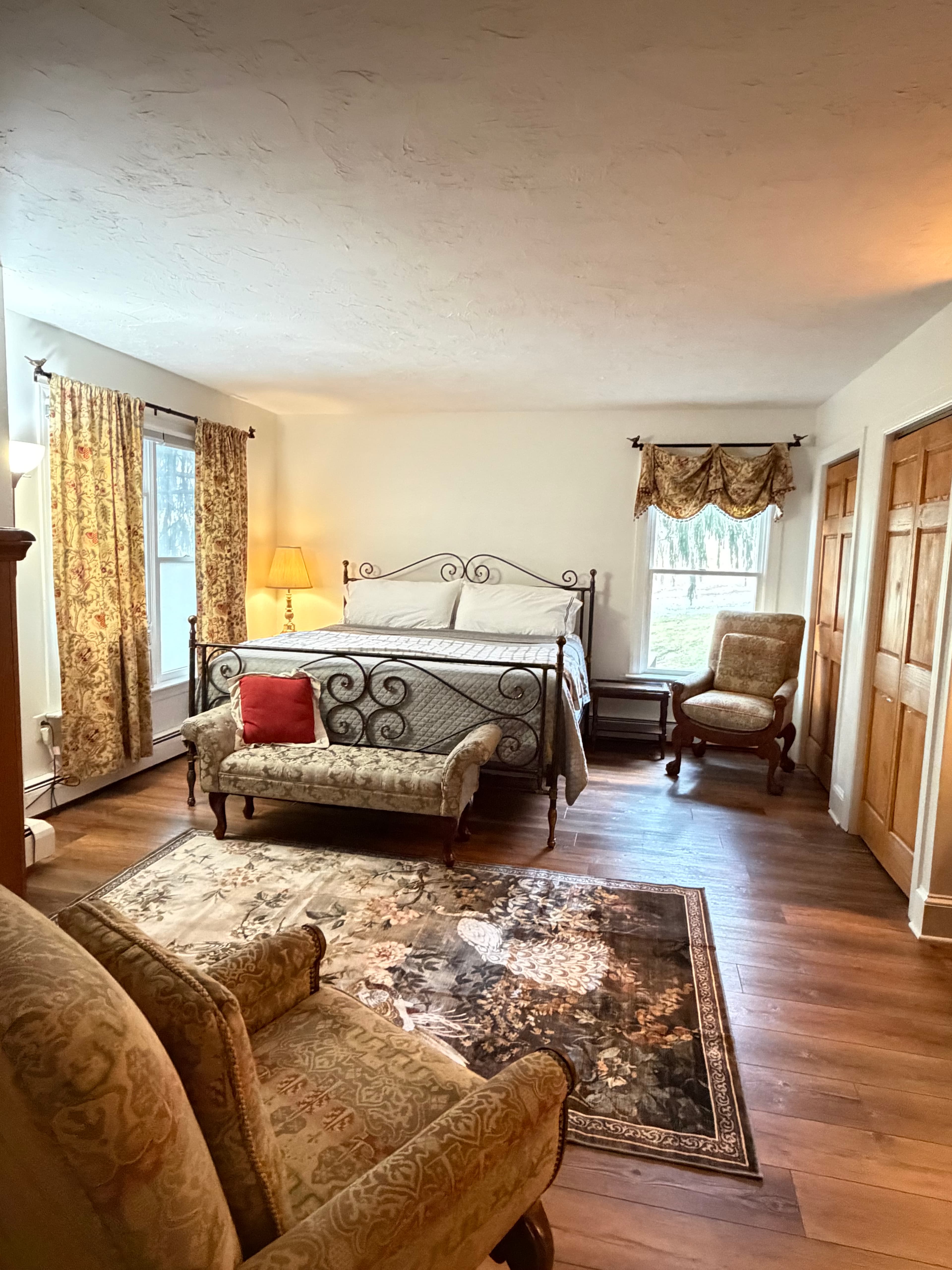 A cozy bedroom featuring a wrought iron bed, a small loveseat, and a patterned rug.