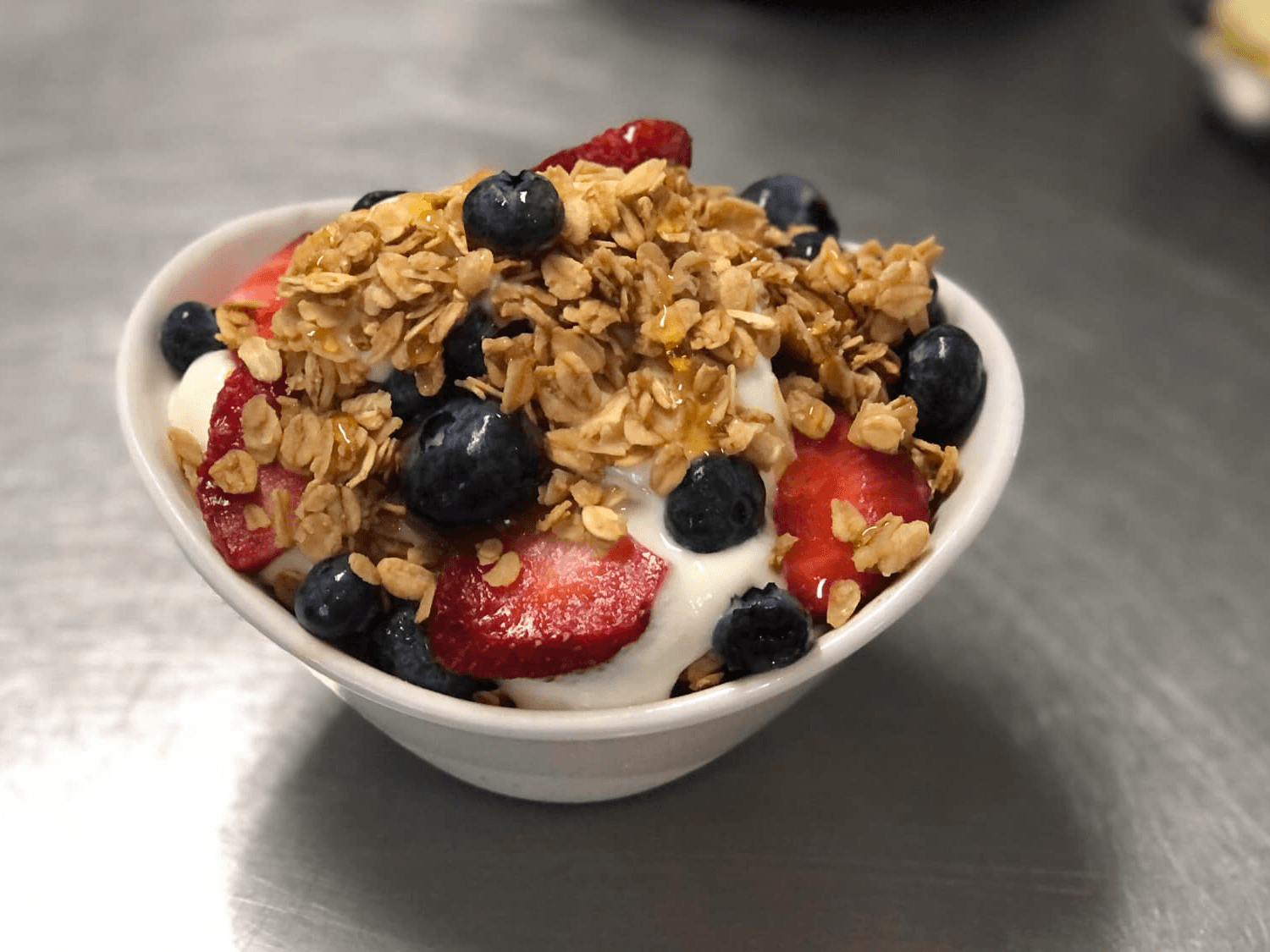 A bowl of yogurt topped with granola, strawberries, and blueberries.