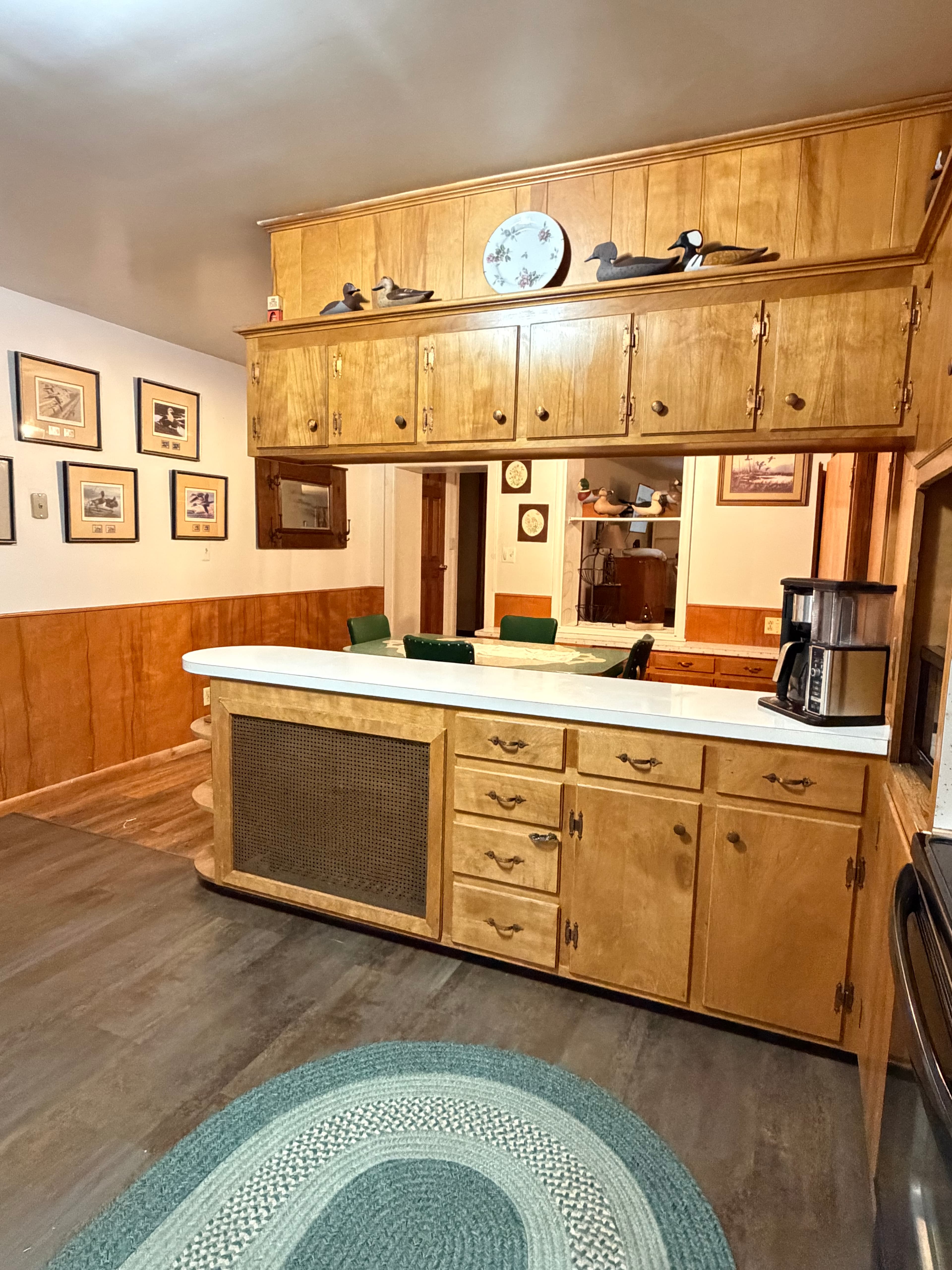 A cozy kitchen featuring wooden cabinets, a marble countertop, and framed artwork on the walls.