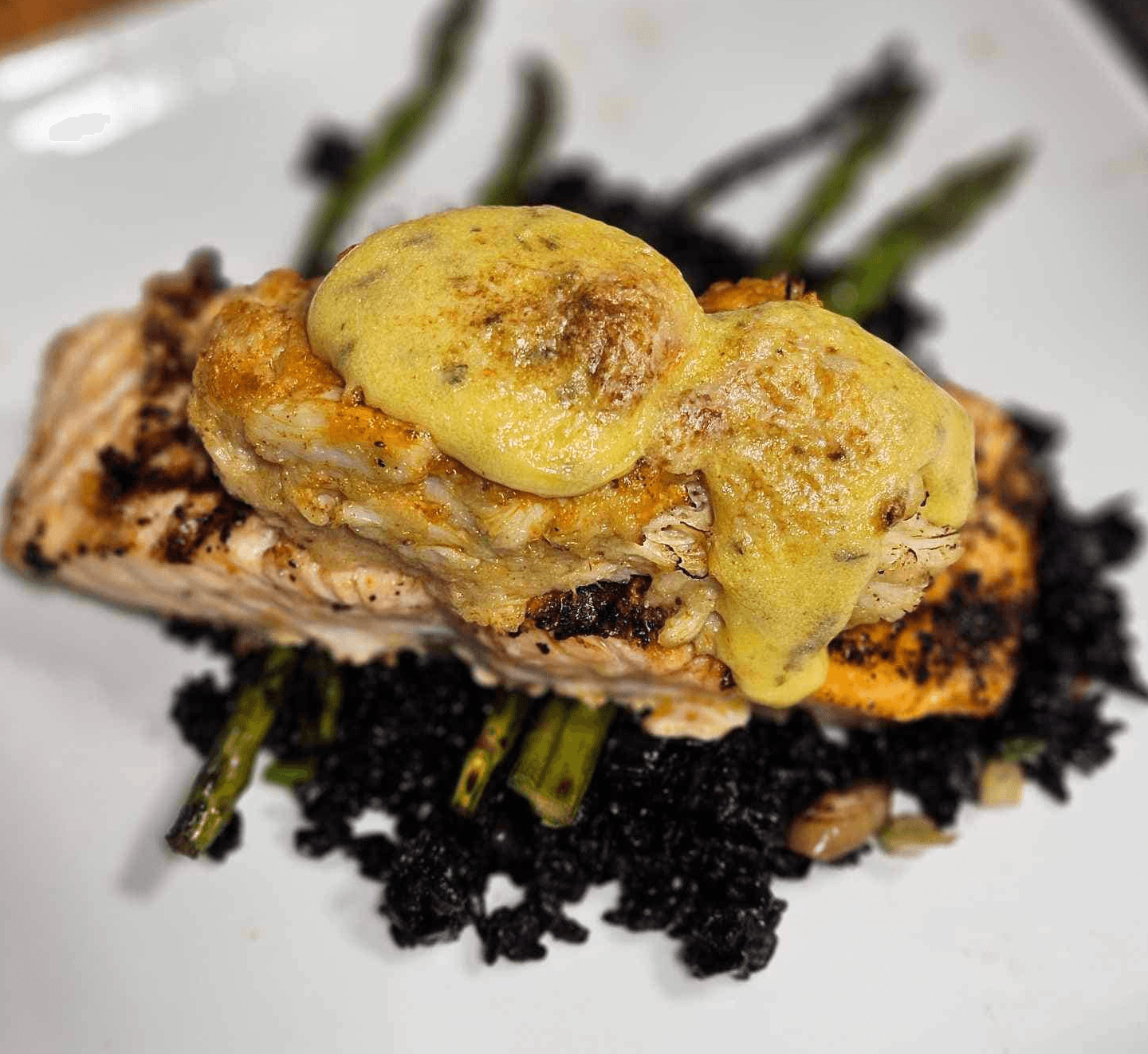 Grilled salmon topped with a creamy sauce served over black rice and asparagus.