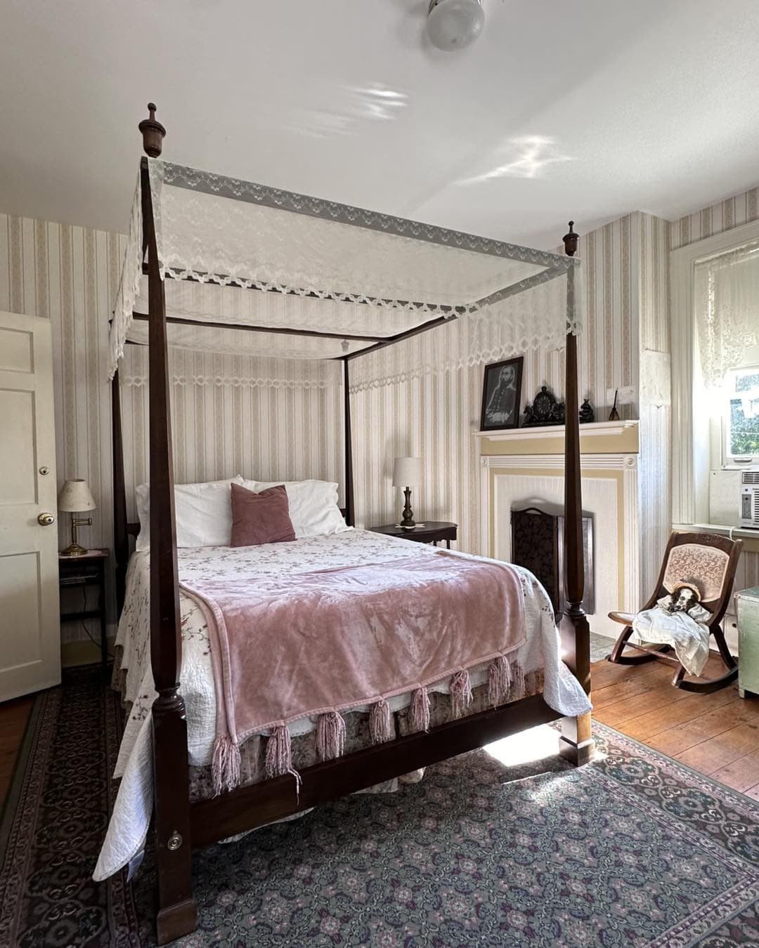 A cozy bedroom featuring a four-poster bed adorned with a pink blanket and vintage decor.